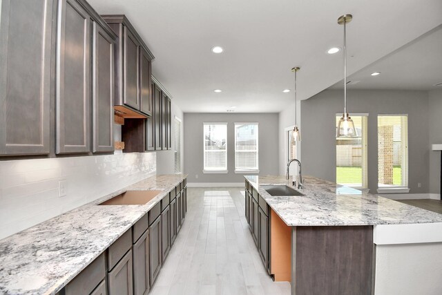 kitchen featuring recessed lighting, a sink, decorative backsplash, and light wood-style flooring