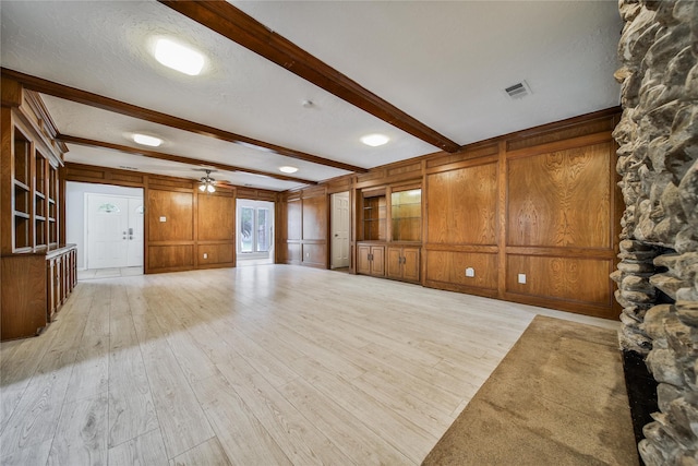 14211 Lakewood Forest Dr, Houston, TX 77070 - unfurnished living room featuring light wood-style floors, beamed ceiling, wood walls, and visible vents