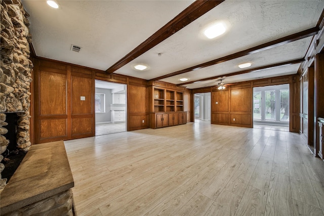 14211 Lakewood Forest Dr, Houston, TX 77070 - unfurnished living room with visible vents, a ceiling fan, wood walls, and beamed ceiling