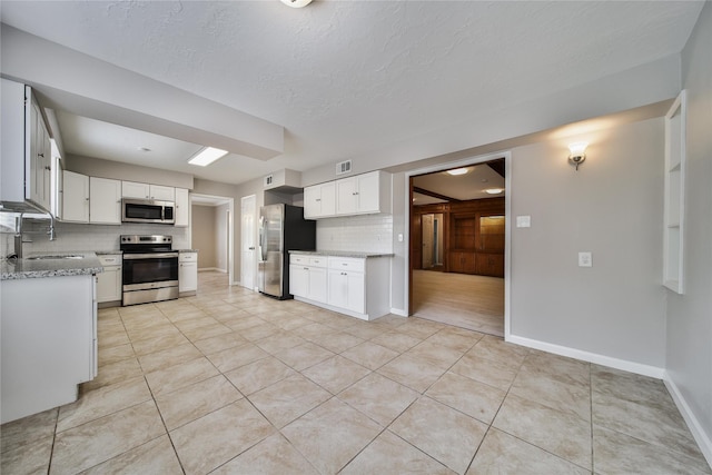 14211 Lakewood Forest Dr, Houston, TX 77070 - kitchen with visible vents, baseboards, tasteful backsplash, a sink, and appliances with stainless steel finishes