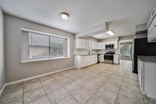 14211 Lakewood Forest Dr, Houston, TX 77070 - kitchen with white cabinets, light stone countertops, a sink, stainless steel appliances, and decorative backsplash