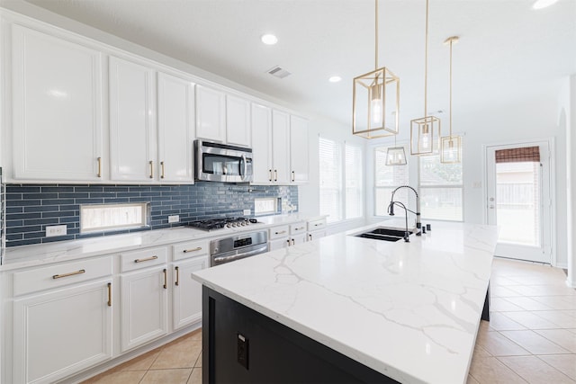 kitchen with white cabinets, light tile patterned flooring, a sink, stainless steel appliances, and decorative backsplash