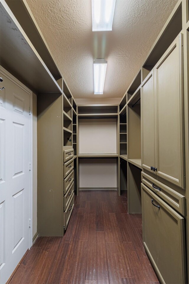 walk in closet with dark wood-style floors