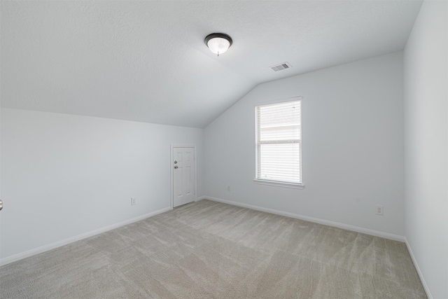 additional living space featuring baseboards, vaulted ceiling, light colored carpet, and visible vents