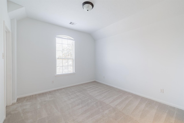 spare room with carpet floors, baseboards, visible vents, and lofted ceiling