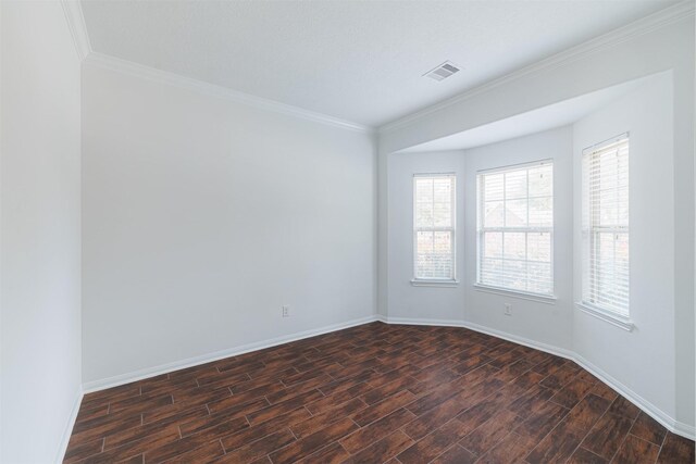 spare room featuring visible vents, dark wood finished floors, crown molding, and baseboards