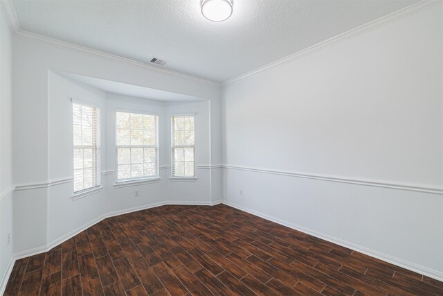 spare room with baseboards, ornamental molding, wood finished floors, and visible vents