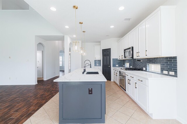kitchen featuring backsplash, stainless steel appliances, white cabinets, and a sink