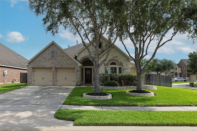 view of front of home with brick siding, a garage, stone siding, a front yard, and driveway
