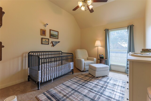 carpeted bedroom with a ceiling fan, baseboards, vaulted ceiling, and a crib