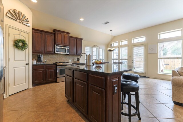 kitchen featuring a sink, a kitchen bar, a wealth of natural light, and stainless steel appliances