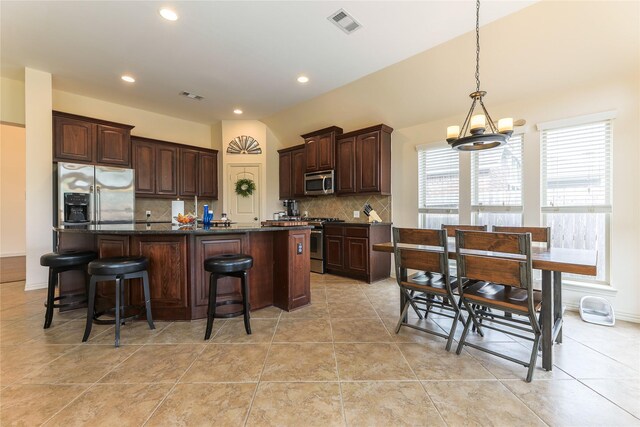kitchen featuring visible vents, dark brown cabinetry, an island with sink, appliances with stainless steel finishes, and backsplash