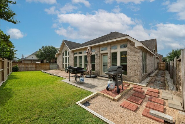 back of house with a patio area, brick siding, a fenced backyard, a yard, and a shingled roof