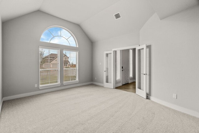 spare room with baseboards, carpet, lofted ceiling, and visible vents