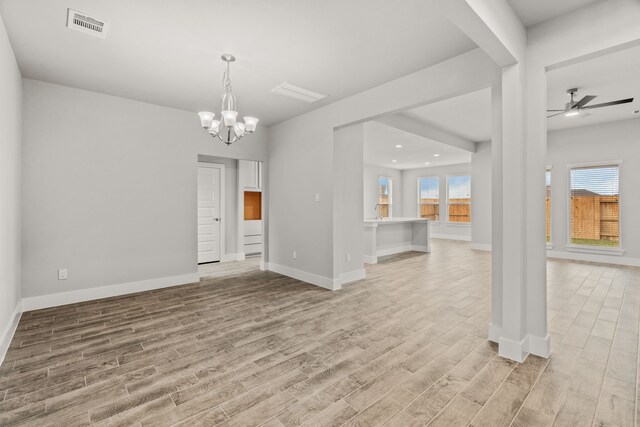 interior space featuring baseboards, visible vents, light wood finished floors, and ceiling fan with notable chandelier