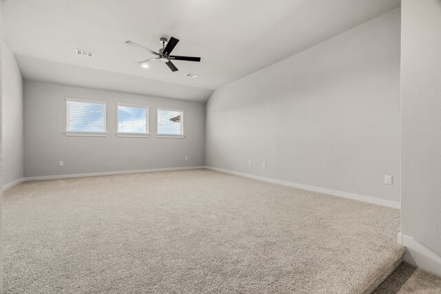 carpeted empty room featuring baseboards, a ceiling fan, lofted ceiling, and visible vents