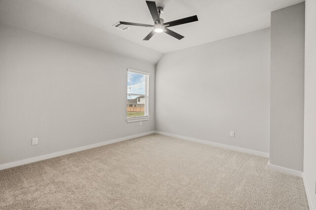 empty room featuring a ceiling fan, light colored carpet, lofted ceiling, and visible vents