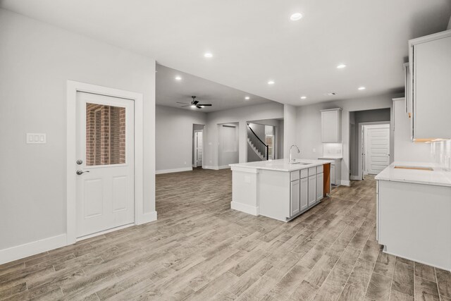 kitchen featuring a sink, recessed lighting, a center island with sink, and light wood finished floors