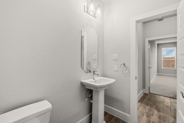 half bath featuring toilet, baseboards, and wood finished floors