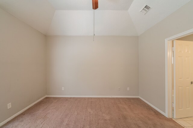 empty room with baseboards, lofted ceiling, light colored carpet, and visible vents