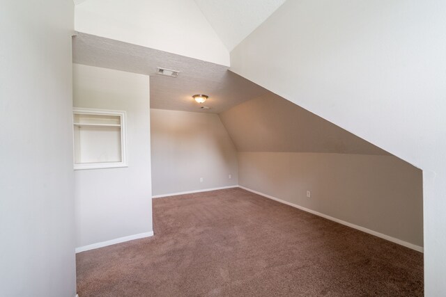 additional living space with baseboards, carpet, vaulted ceiling, and visible vents