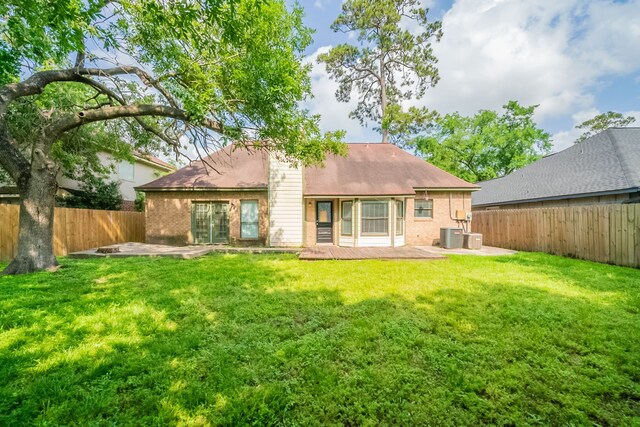 back of property featuring a lawn, a patio, brick siding, and a fenced backyard