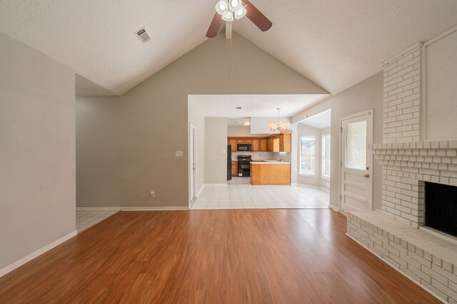 unfurnished living room with vaulted ceiling with beams, ceiling fan with notable chandelier, light wood-type flooring, and visible vents