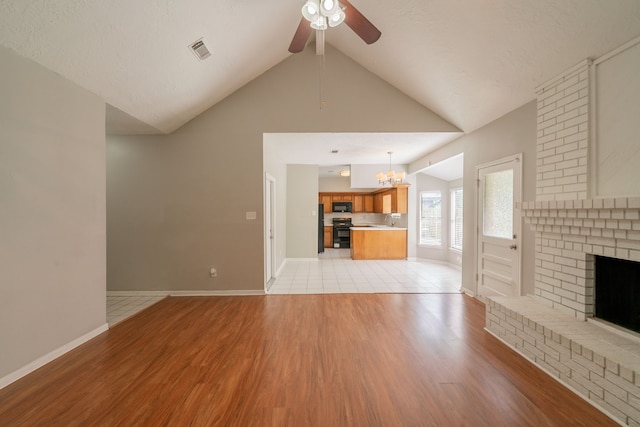 18927 Sandia Pines Dr, Humble, TX 77346 - unfurnished living room with light wood-type flooring, ceiling fan, a chandelier, and a brick fireplace