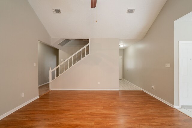 unfurnished living room featuring light wood-style flooring, stairs, a ceiling fan, lofted ceiling, and visible vents