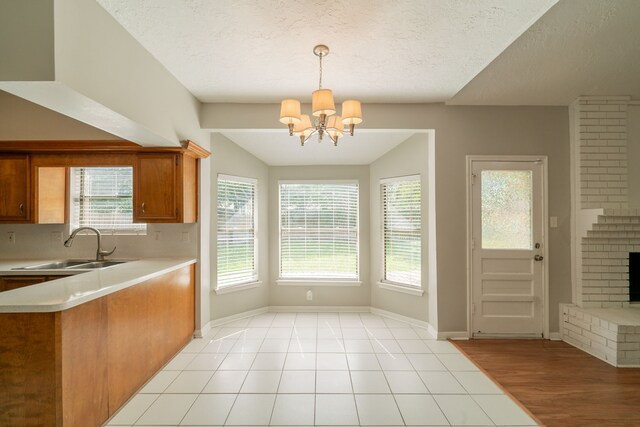 kitchen with brown cabinetry, a sink, a wealth of natural light, and light countertops