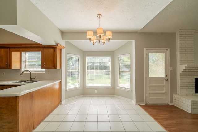 18927 Sandia Pines Dr, Humble, TX 77346 - kitchen with a sink, brown cabinetry, light countertops, a chandelier, and baseboards