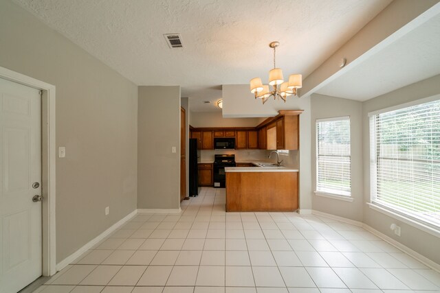 kitchen featuring an inviting chandelier, light countertops, brown cabinets, a sink, and black appliances