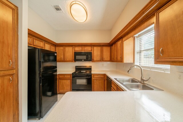 kitchen featuring brown cabinetry, visible vents, a sink, light countertops, and black appliances