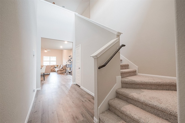 staircase featuring baseboards, ceiling fan, and wood finished floors