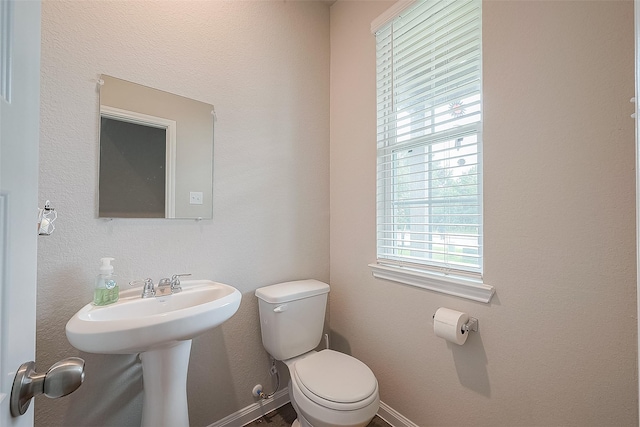 half bath with a sink, baseboards, and toilet