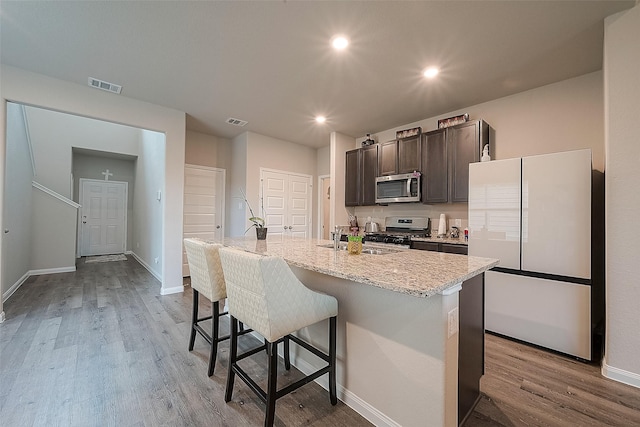 kitchen with visible vents, wood finished floors, a breakfast bar, a sink, and appliances with stainless steel finishes