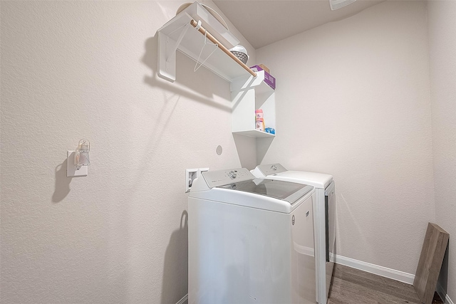 clothes washing area with washing machine and clothes dryer, laundry area, baseboards, and wood finished floors