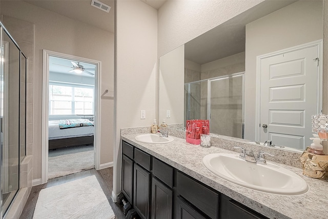 ensuite bathroom featuring a sink, a stall shower, wood finished floors, and visible vents