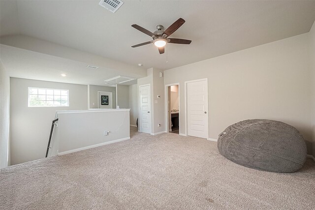 unfurnished room with visible vents, attic access, a ceiling fan, carpet, and an upstairs landing