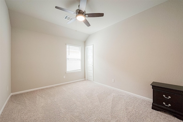 spare room featuring visible vents, lofted ceiling, light carpet, baseboards, and ceiling fan