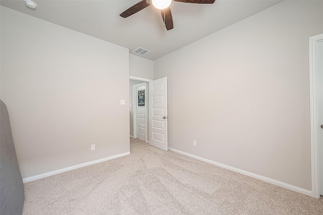 carpeted spare room with ceiling fan, visible vents, and baseboards