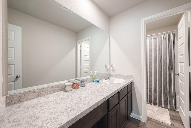 bathroom with visible vents, vanity, wood finished floors, baseboards, and a shower with shower curtain