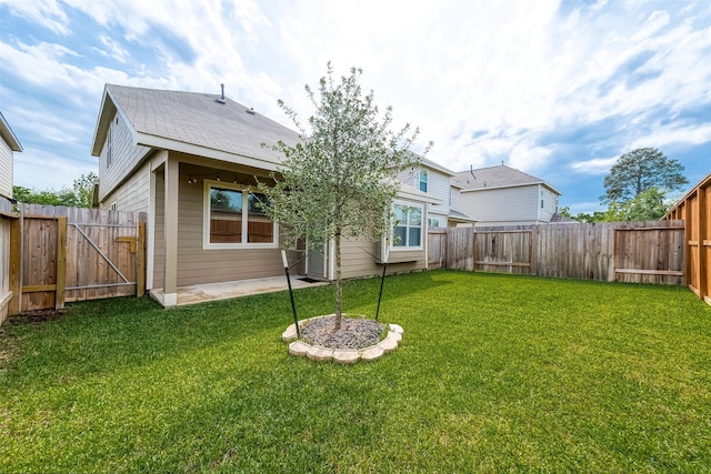 rear view of house with a lawn, a gate, a fenced backyard, and a patio area