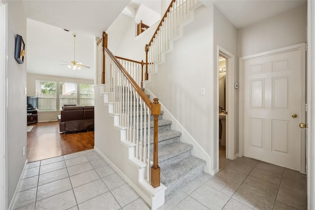 staircase with baseboards, ceiling fan, and tile patterned floors