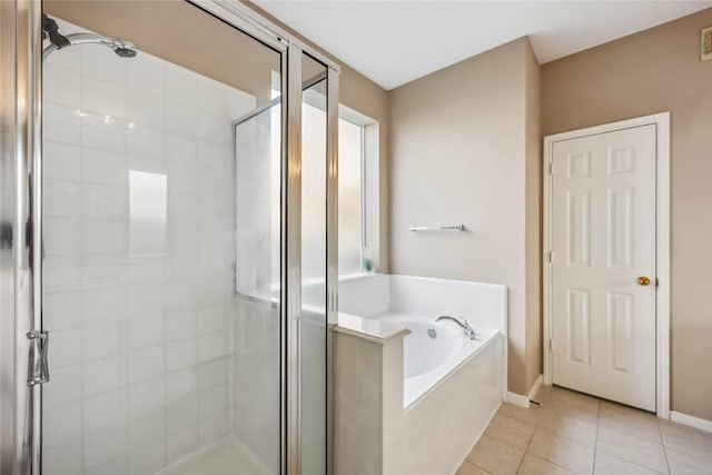 bathroom with baseboards, tile patterned flooring, a garden tub, and a stall shower