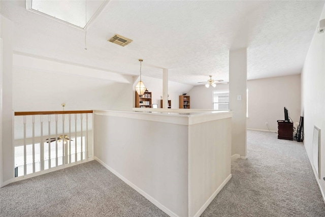 hallway featuring carpet floors, attic access, baseboards, vaulted ceiling, and visible vents