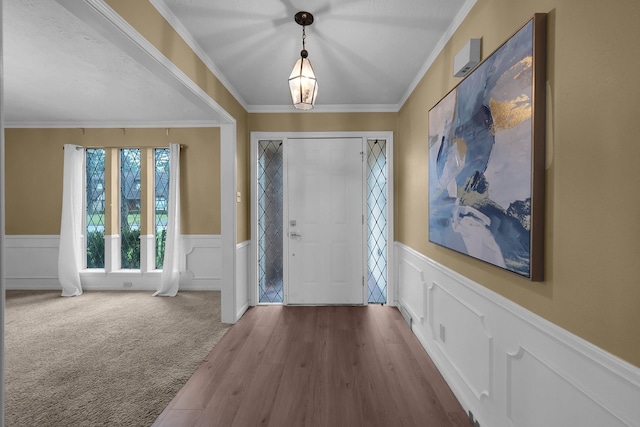 entrance foyer featuring crown molding, wainscoting, wood finished floors, and a decorative wall