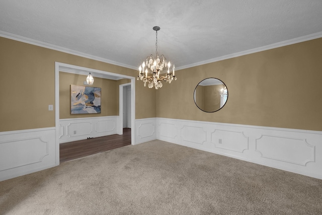 unfurnished dining area with carpet flooring, crown molding, an inviting chandelier, and wainscoting