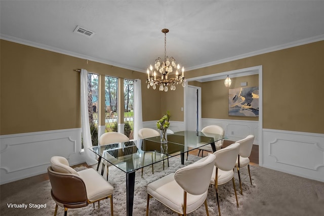 dining space featuring ornamental molding, wainscoting, a chandelier, and visible vents