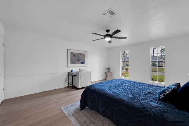 bedroom featuring visible vents, baseboards, ceiling fan, and wood finished floors
